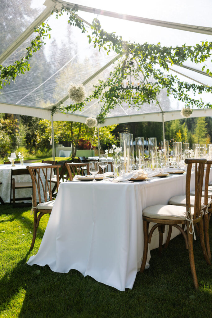 Outdoor wedding reception table setup under a clear tent in daylight