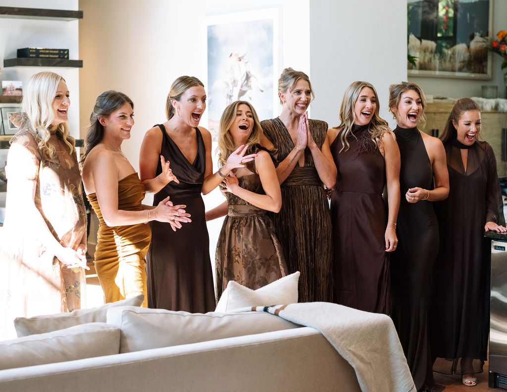 Bride getting ready with her bridesmaids watching in excitement