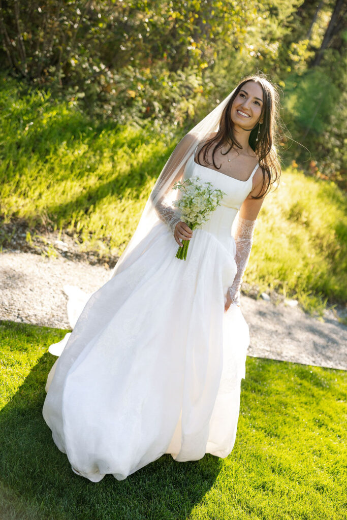 Bride standing in sunlight holding her bouquet on the lawn