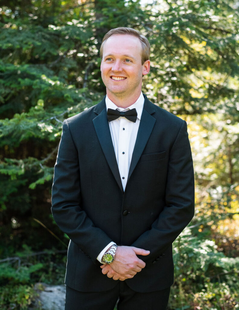 Groom portrait in a black tuxedo standing in natural light
