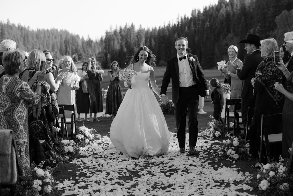 Bride and groom walking up the floral-lined ceremony aisle after being announced married