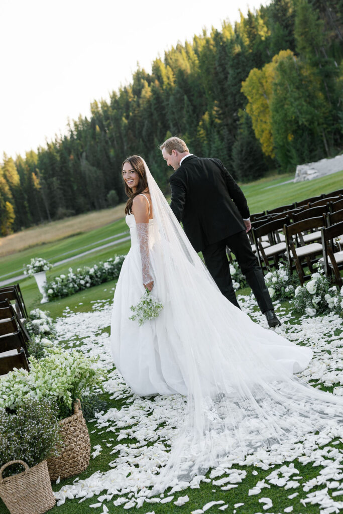 Bride and groom standing in their ceremony aisle with mountain views behind them