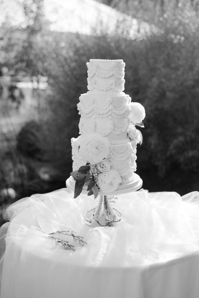 Black and white photo of the ornate tiered wedding cake on a table