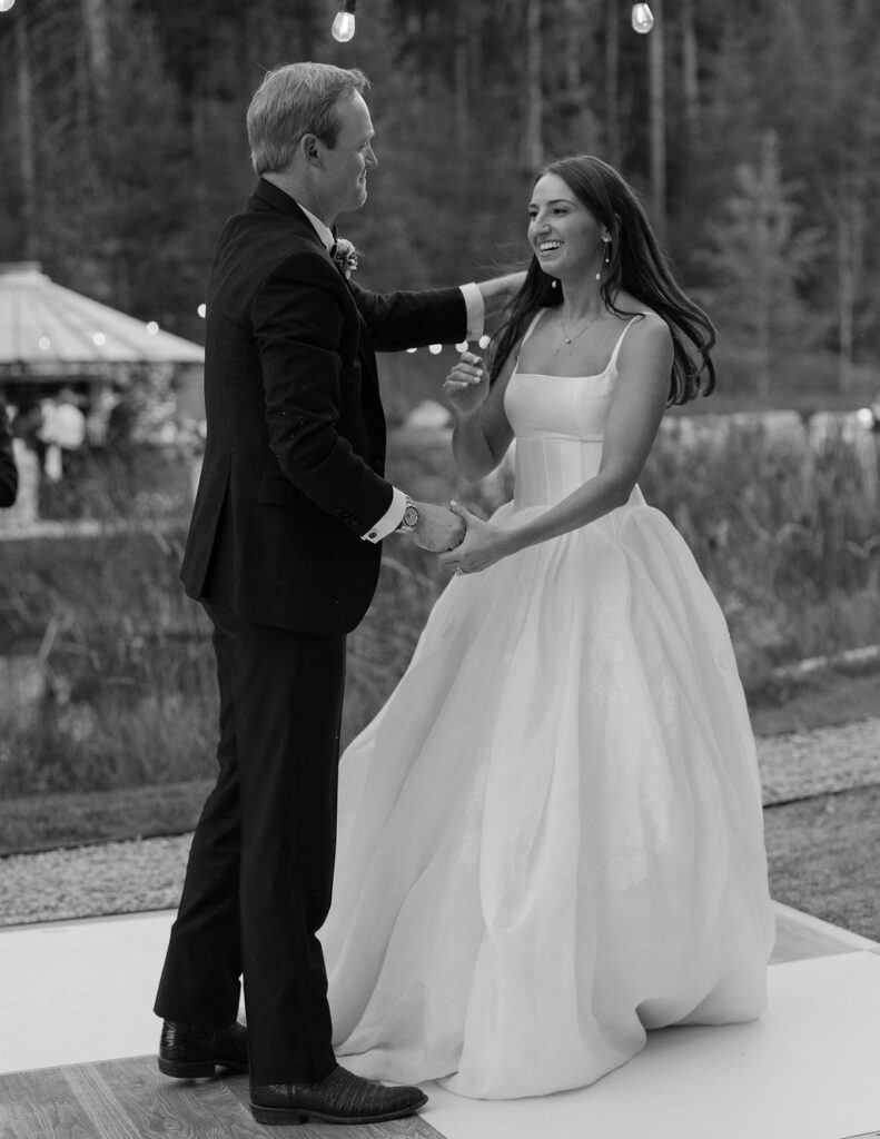 Bride smiling while dancing with the groom on the outdoor dance floor
