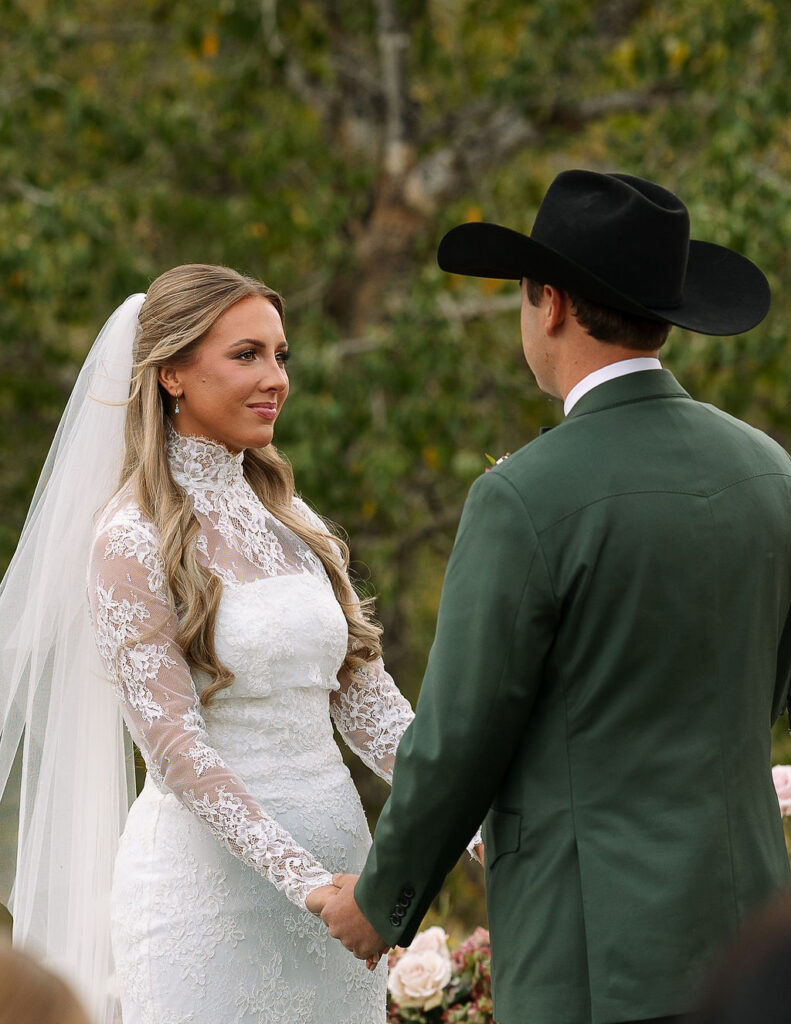 Bride and groom holding hands during outdoor ceremony at The Meadows on Rock Creek