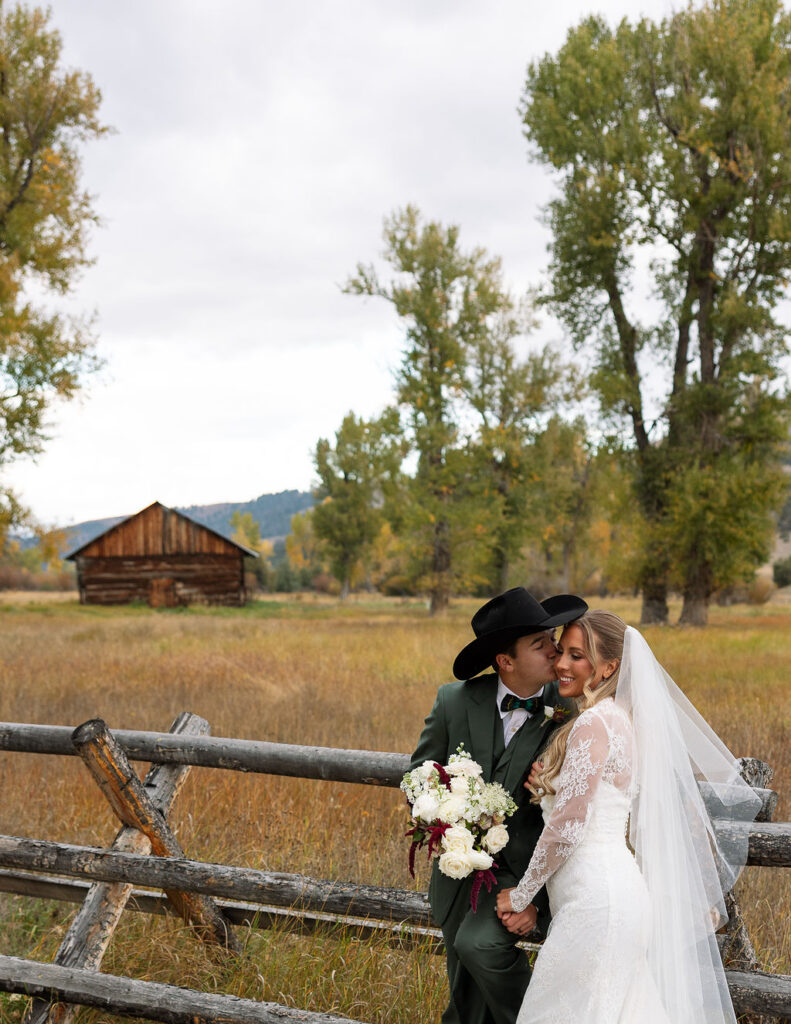 Bride and groom portrait by wooden fence at The Meadows on Rock Creek Montana wedding venue