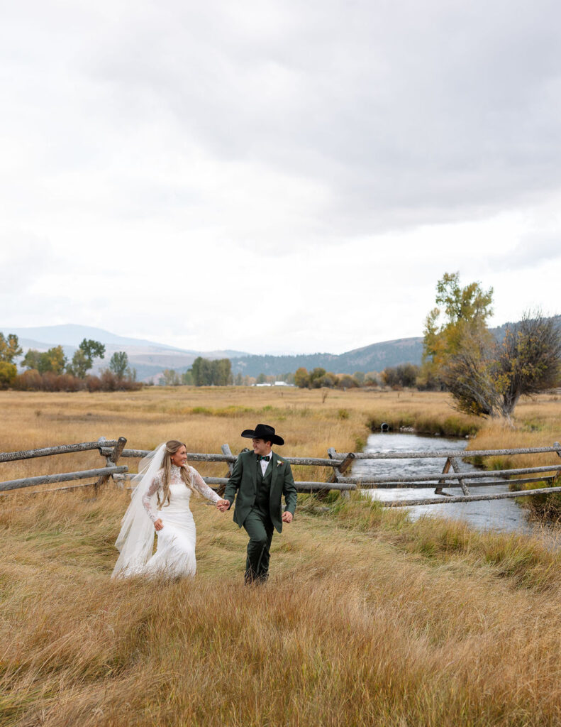 Bride and groom walking through meadow at The Meadows on Rock Creek Montana wedding