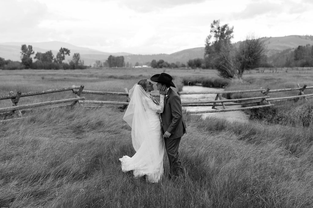 Bride and groom embracing in tall grass during The Meadows on Rock Creek wedding