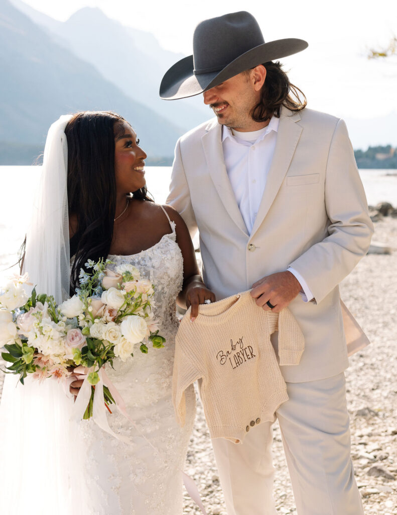 Bride and groom smiling together while holding bouquet during Glacier National Park elopement