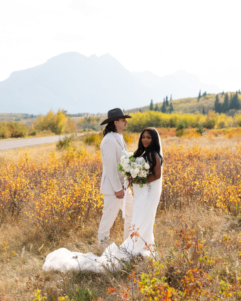 Bride and groom standing together in a golden meadow during Glacier National Park fall elopement