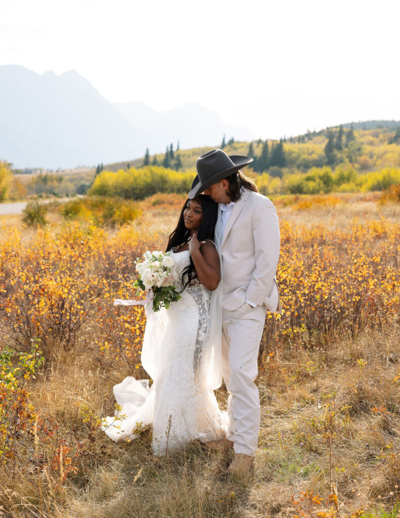 Bride and groom embracing in a golden field during fall elopement in Glacier National Park