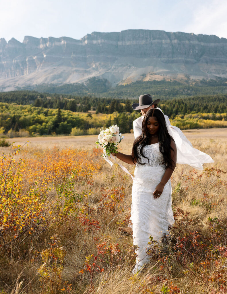 Bride walking through golden fall foliage in Glacier National Park holding wedding bouquet