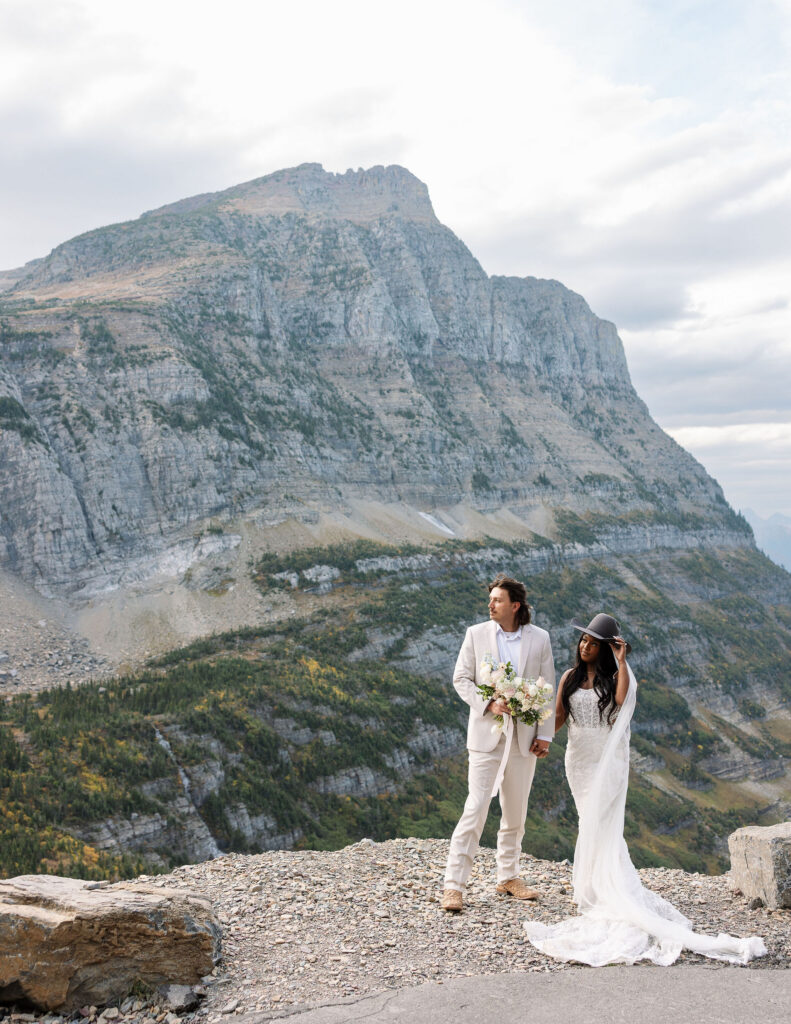 Bride and groom posing with dramatic mountain views during a Glacier National Park fall elopement