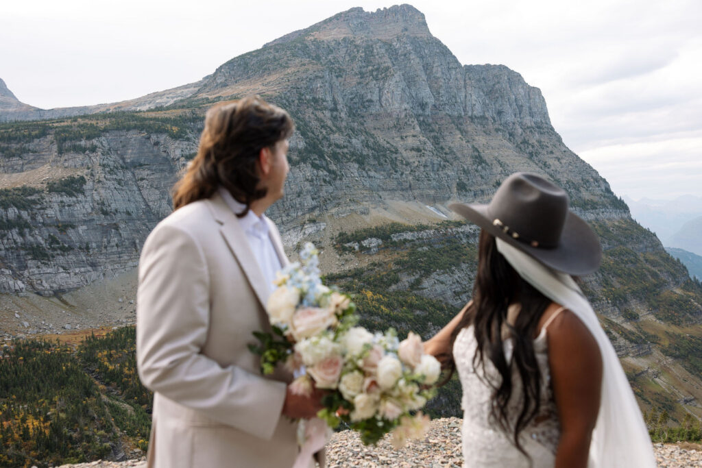 Bride and groom embracing on mountain road during fall elopement in Glacier National Park