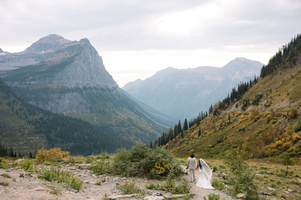 Bride walking along mountain trail in Glacier National Park during fall elopement