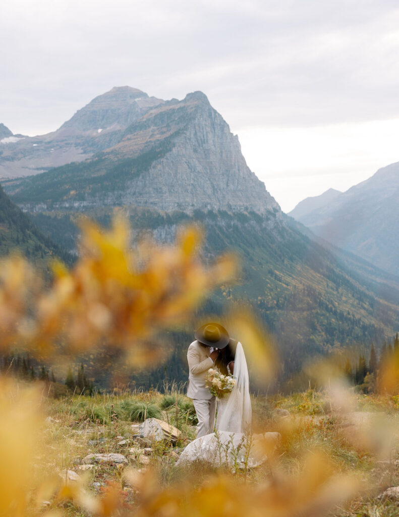 Bride and groom embracing with sweeping mountain views during Glacier National Park fall elopement