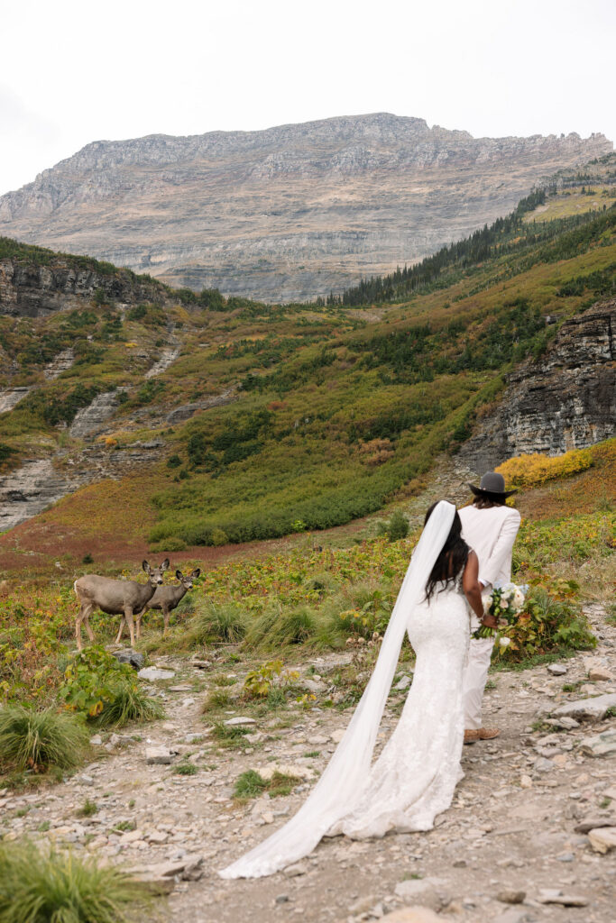 Bride walking along mountain trail with long veil during fall elopement in Glacier National Park