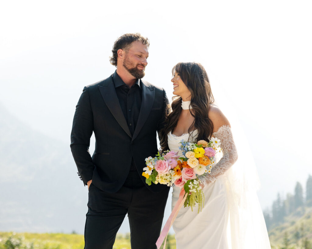 Bride and groom smiling together while holding a colorful bouquet during a Glacier National Park elopement