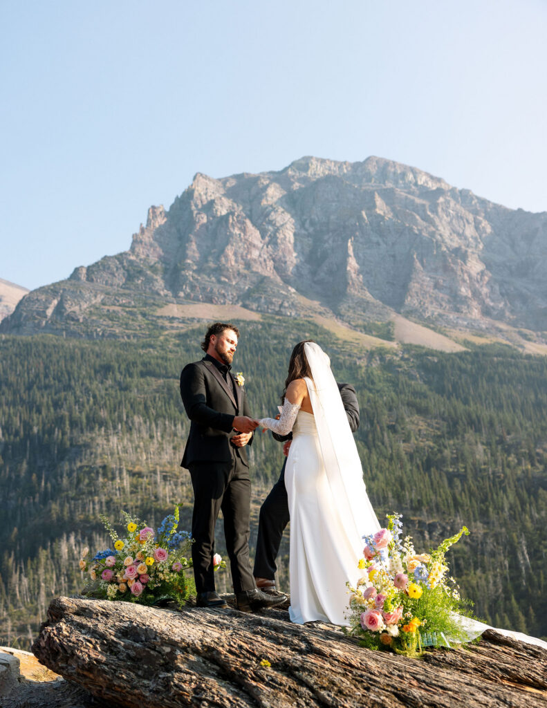 Bride and groom holding hands during their Glacier National Park elopement ceremony with mountain backdrop