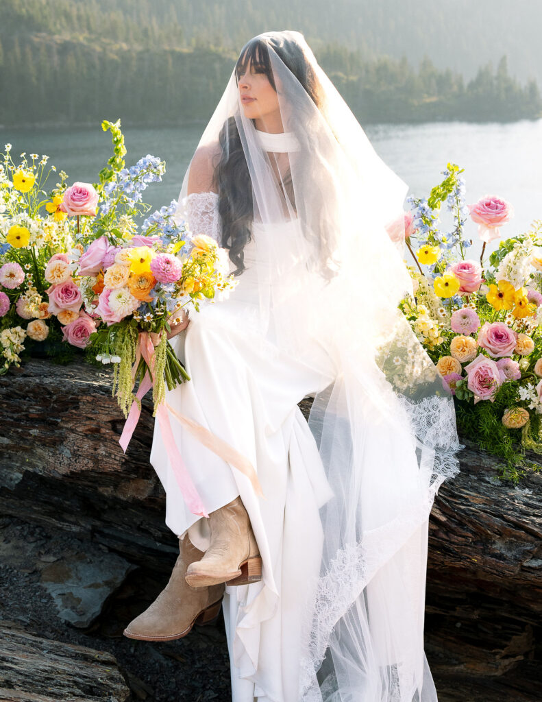 Bride stepping down from a rocky ledge surrounded by vibrant florals during a Glacier National Park elopement