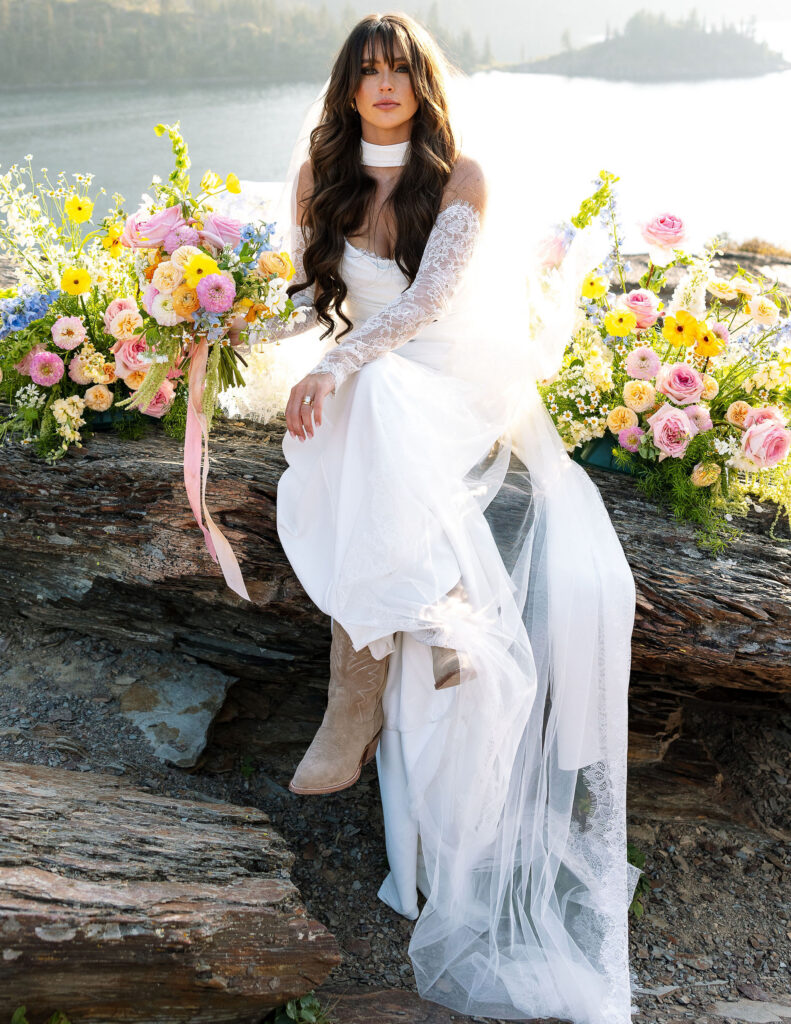 Bride sitting on a rocky overlook surrounded by colorful florals during a Glacier National Park elopement