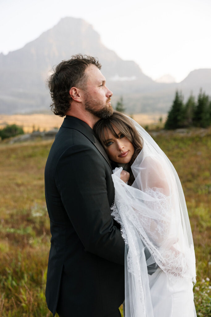 Bride resting her head on groom’s shoulder in an alpine meadow during their Glacier National Park elopement