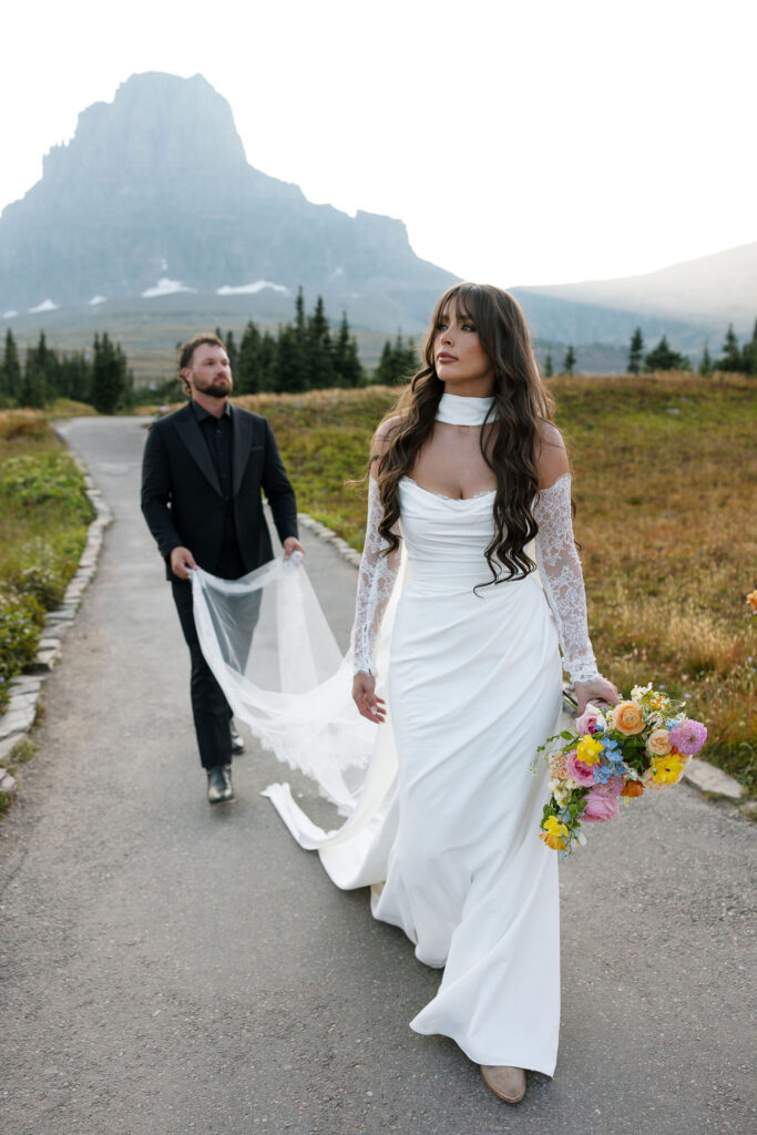Bride and groom walking together along a scenic road in Glacier National Park during their elopement