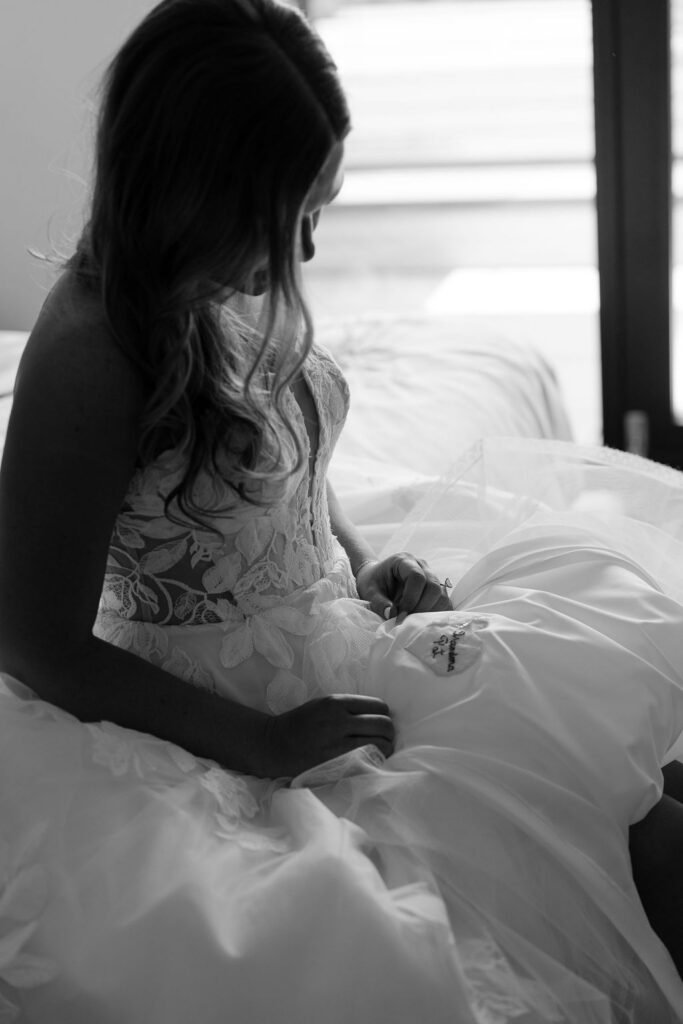 Black and white portrait of bride sitting on a bed in her wedding dress during the getting ready moments