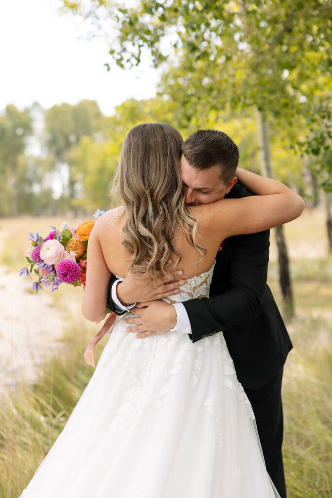 Bride and groom hugging during sunset portraits with colorful bouquet in Whitefish Montana