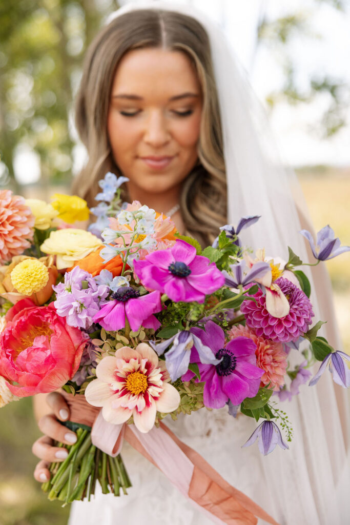 Close-up portrait of bride holding a vibrant colorful bouquet during a summer wedding in Whitefish Montana