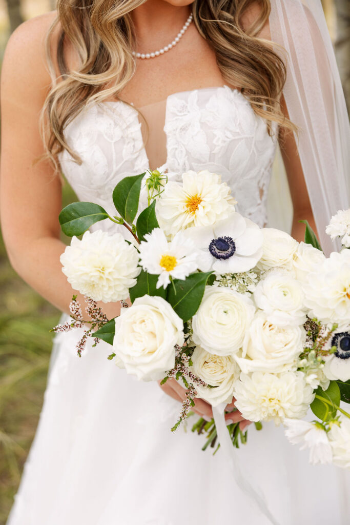 Close-up of a white bridal bouquet with roses and greenery during a summer wedding in Whitefish Montana