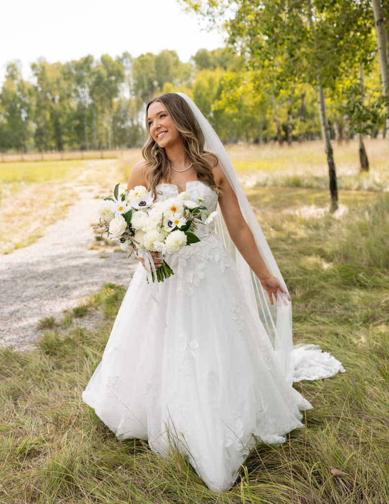Bride walking along a path holding a white bouquet during sunset portraits in Whitefish Montana