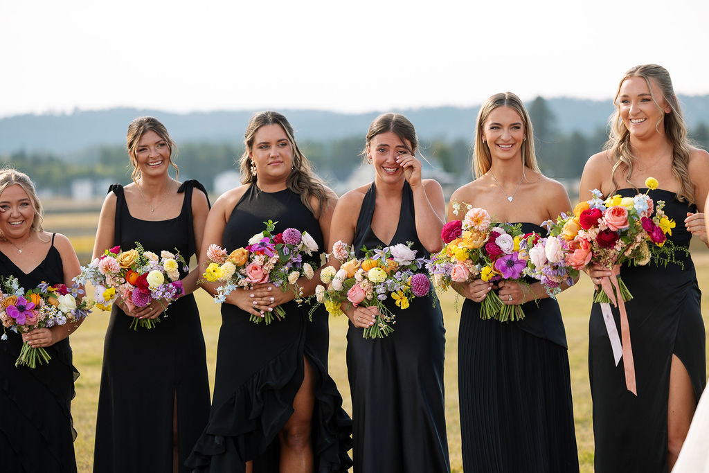 Bridesmaids standing together holding colorful bouquets during an outdoor wedding ceremony in Whitefish Montana