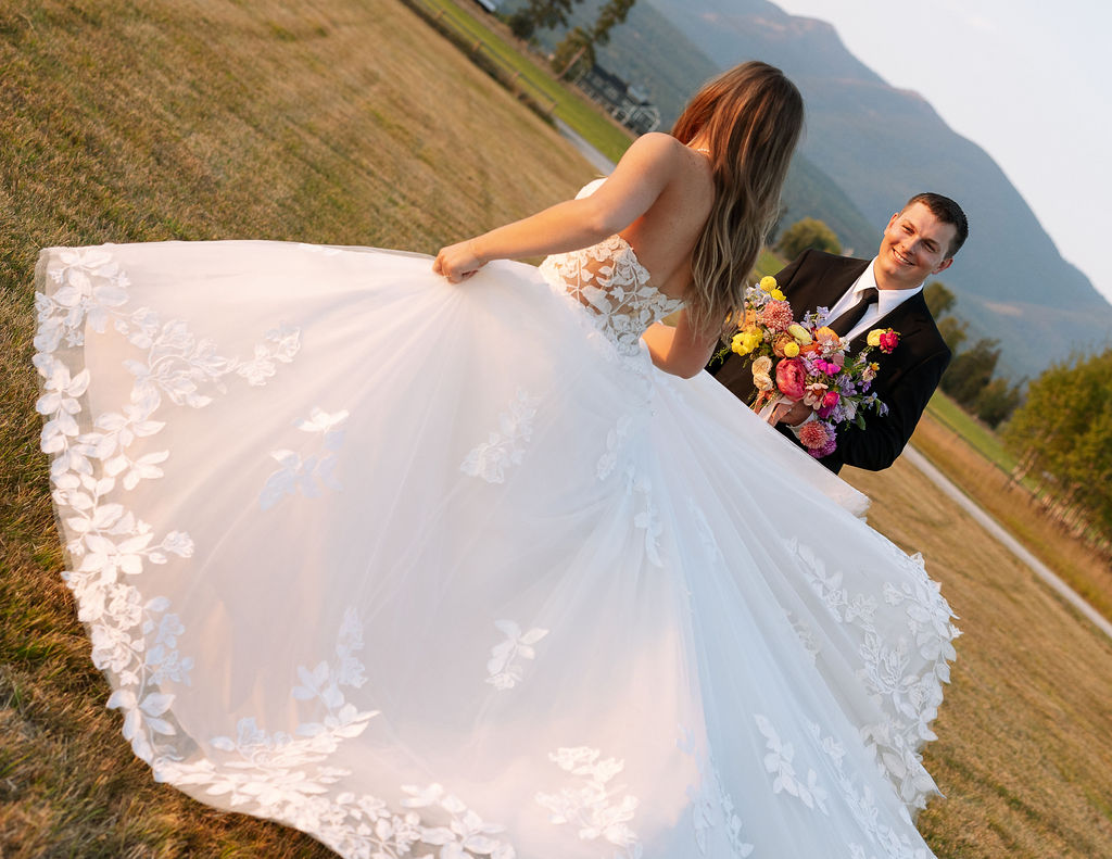Bride and groom walking through an open field with mountains in the background during sunset portraits in Whitefish Montana