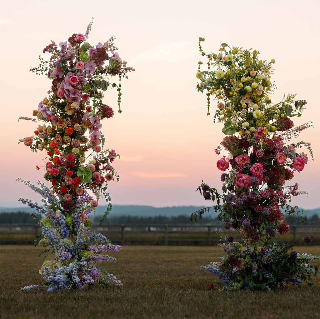 Colorful floral ceremony installations standing in an open field at sunset during a summer wedding in Whitefish Montana photographed by Haley Jessat