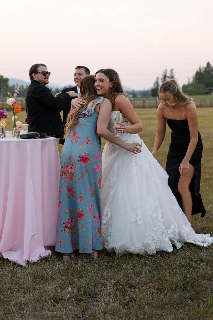 Bride standing with friends and bridesmaids during cocktail hour at a summer wedding celebration in Whitefish Montana photographed by Haley Jessat