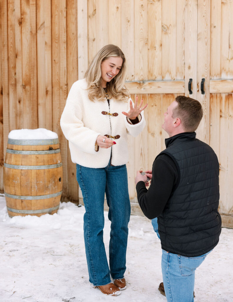 Man kneeling in the snow proposing to his girlfriend during a winter proposal in Whitefish Montana