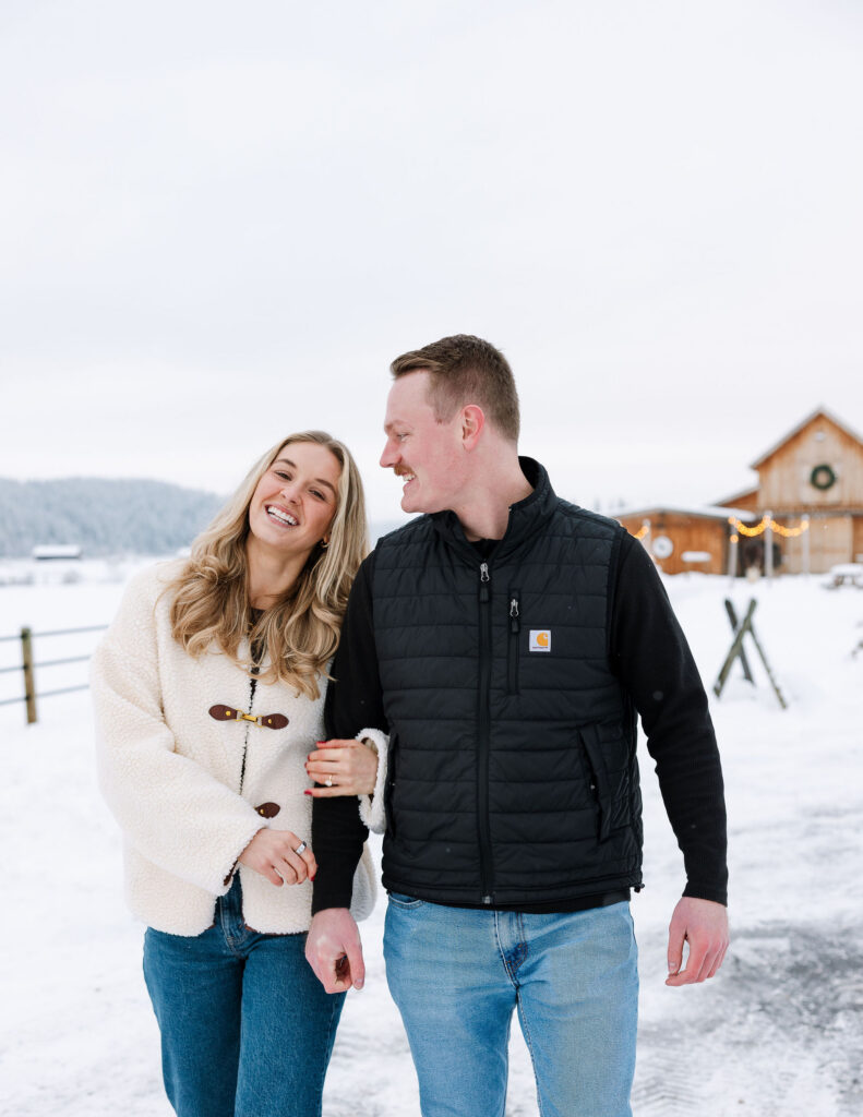 Couple walking together in the snow after a winter proposal in Whitefish Montana