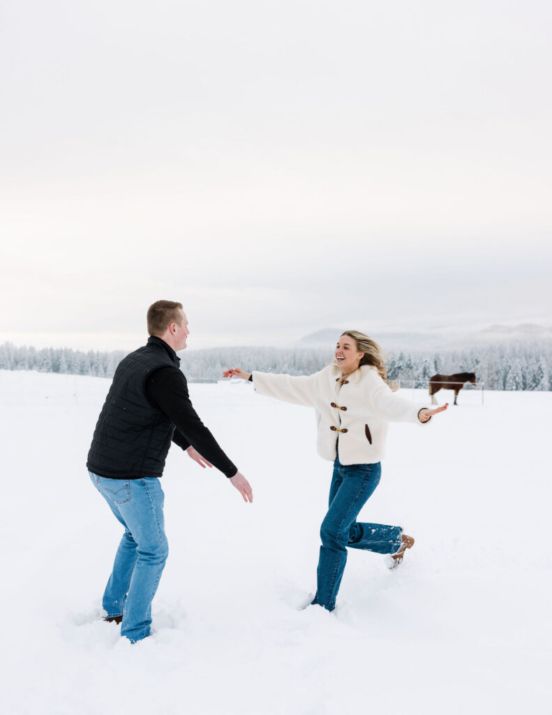 Couple running toward each other in snowy field after winter proposal in Whitefish Montana