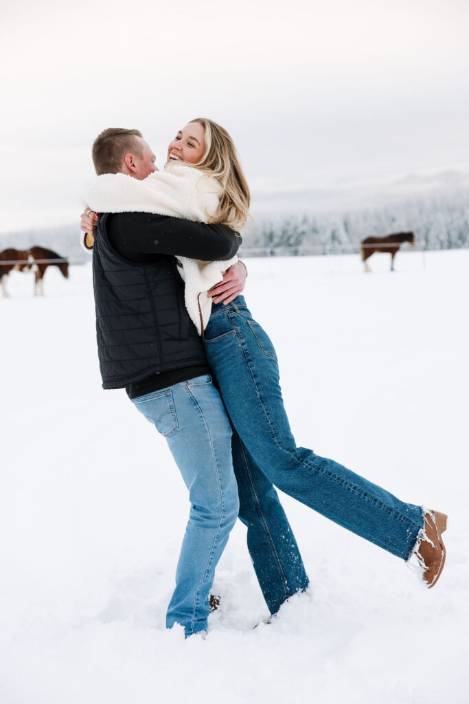 Man lifting woman in celebration after winter proposal in Whitefish Montana