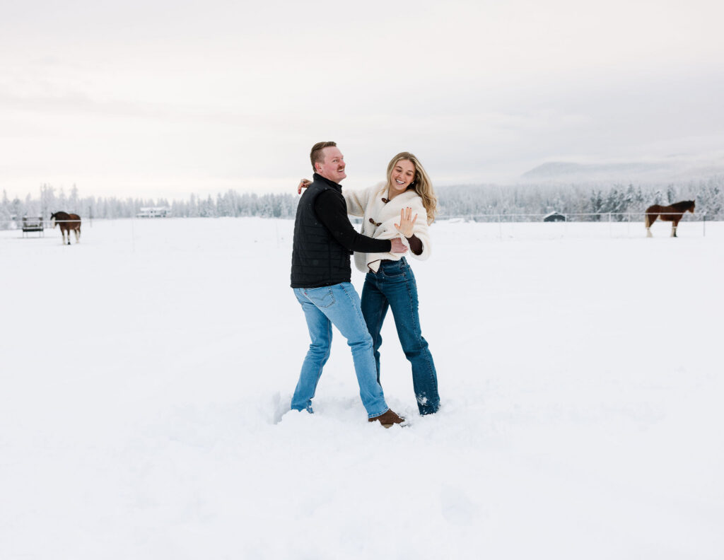 Couple walking together in snowy mountain field after proposal in Whitefish Montana