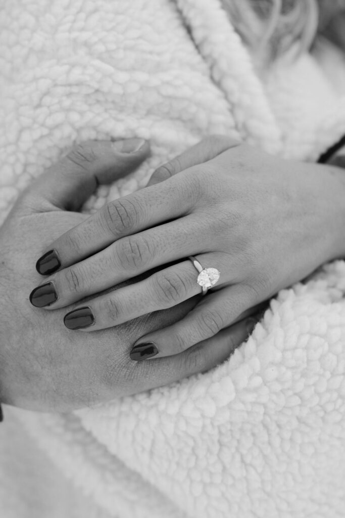 Black and white close up of engagement ring on woman’s hand after proposal in Whitefish Montana